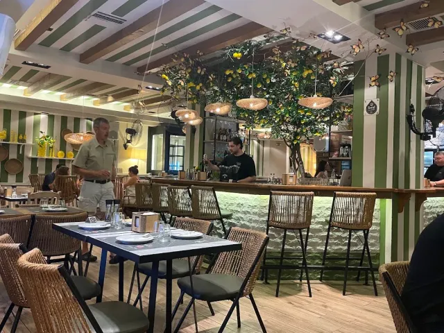 A space with green and white striped walls, a lemon tree above the counter and wicker chairs
