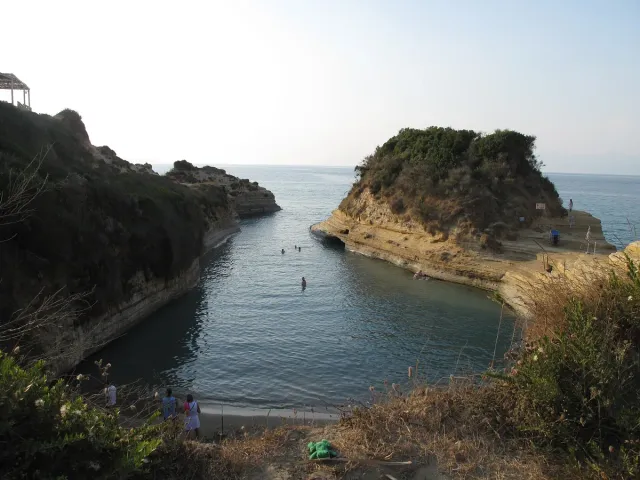 A narrow water corridor cut between sandstone cliffs, with people on the rocks on both sides