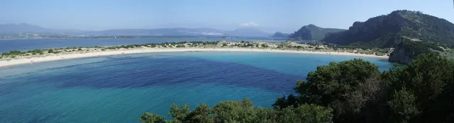 An arc shaped bay with pale sand and shallow water in shades of blue