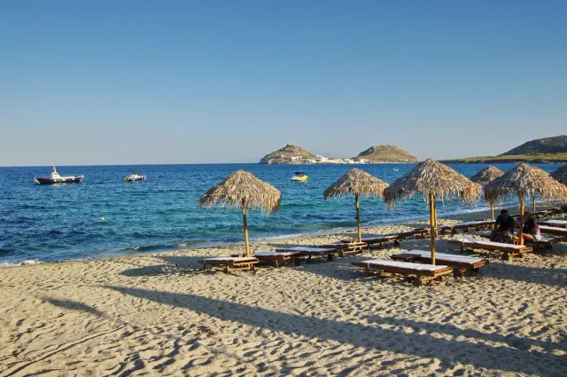 Straw parasols and sunbeds on a sandy beach facing blue sea