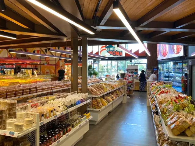 A shop hall with shelves loaded with packaged baked goods and a wooden beam ceiling