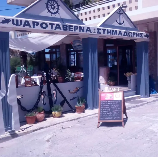A blue and white frontage with an anchor and chain, pots outside and a handwritten menu board