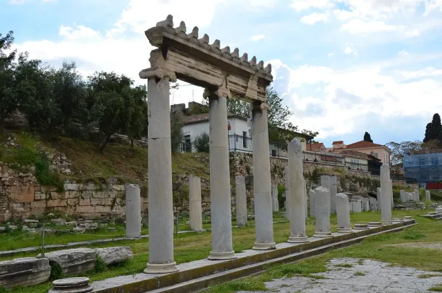 Column remains and scattered marble blocks in an open precinct under a bright sky