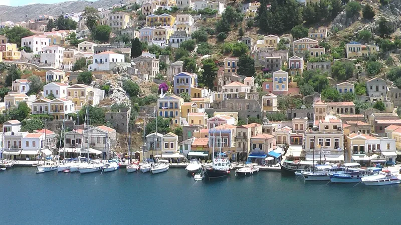 Pastel neoclassical houses climbing a steep slope above a harbour full of boats