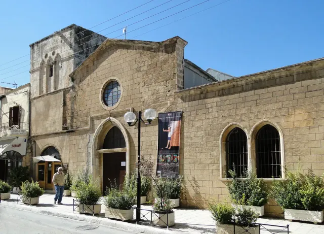 A Venetian stone building with arched windows housing a museum, with trees in front