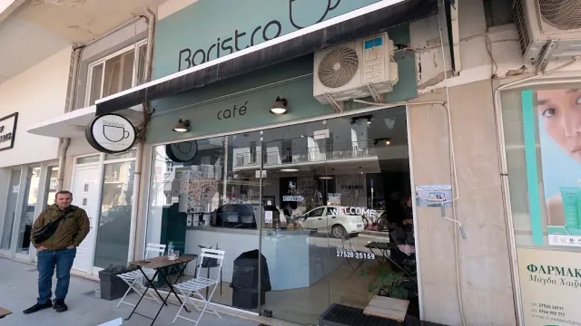 A mint coloured front with a sign and a display window, and a small table on the pavement