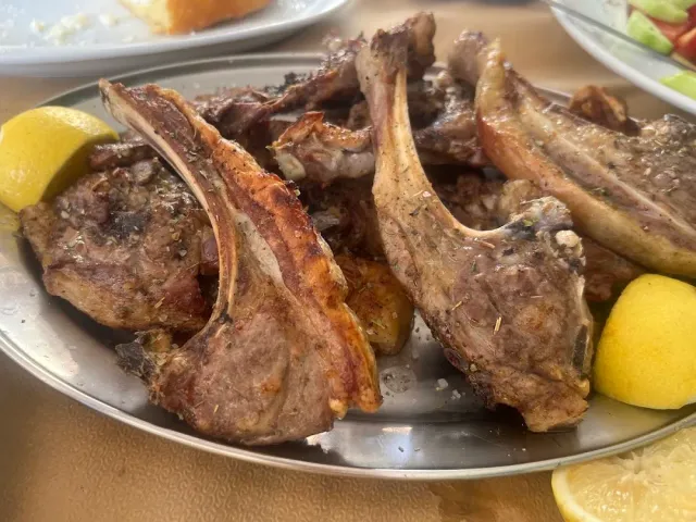 A metal platter with grilled lamb chops and lemon wedges at the edges
