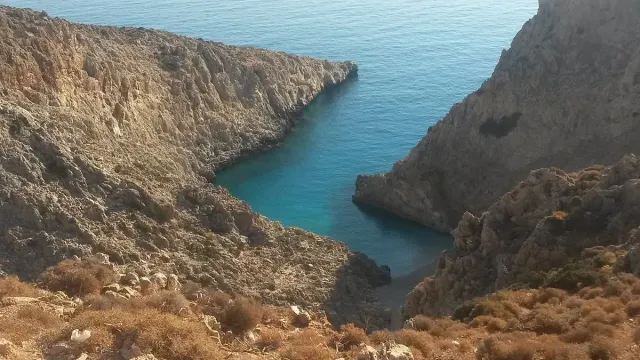 A narrow deep inlet between high rock cliffs, with turquoise water