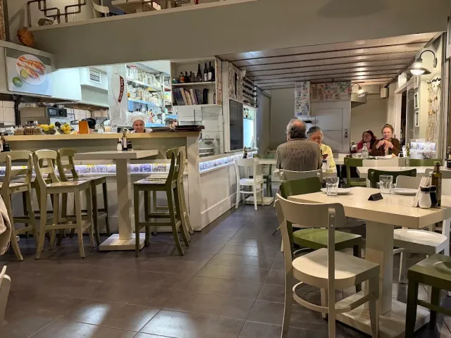 A bright dining room with a counter, high stools and diners seated at tables