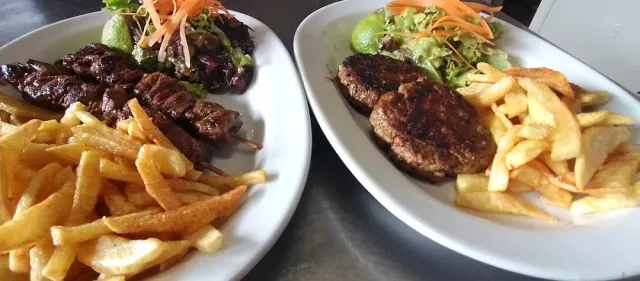 Two plates with grilled meat, fried potatoes and a green salad on the side