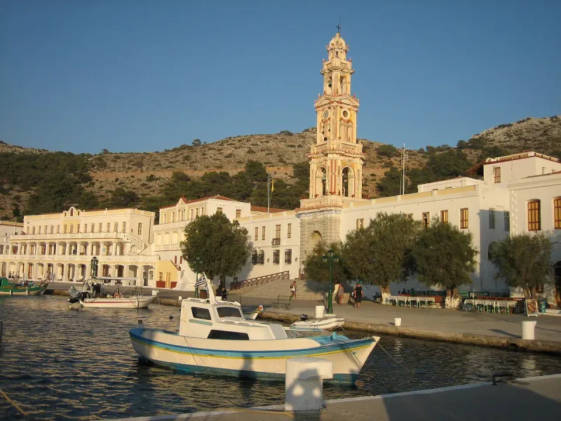 A monastery complex with a bell tower on a bay and a boat moored in front