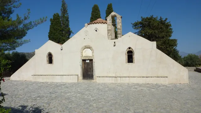 A whitewashed Byzantine church with tiled roofs and stone arches
