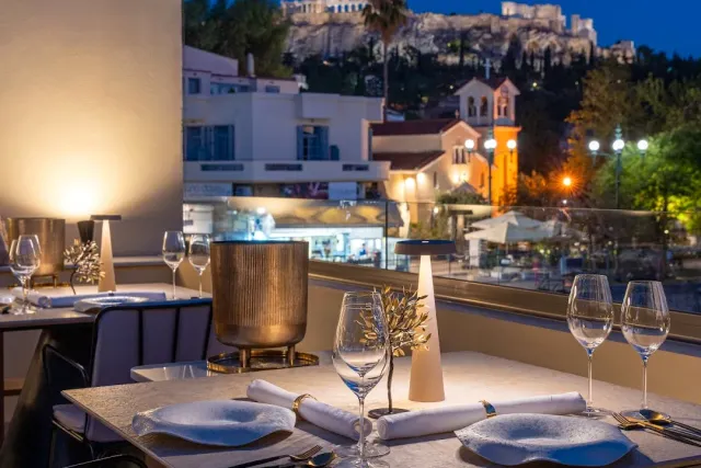 A set table on a terrace in the evening, and behind it a lit hill with temple ruins