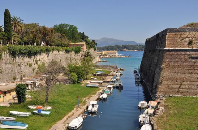 Stone fortress walls above a water channel with small boats