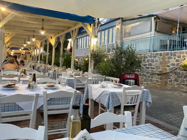 A long veranda with tables in blue checked cloths, white chairs and hanging lamps