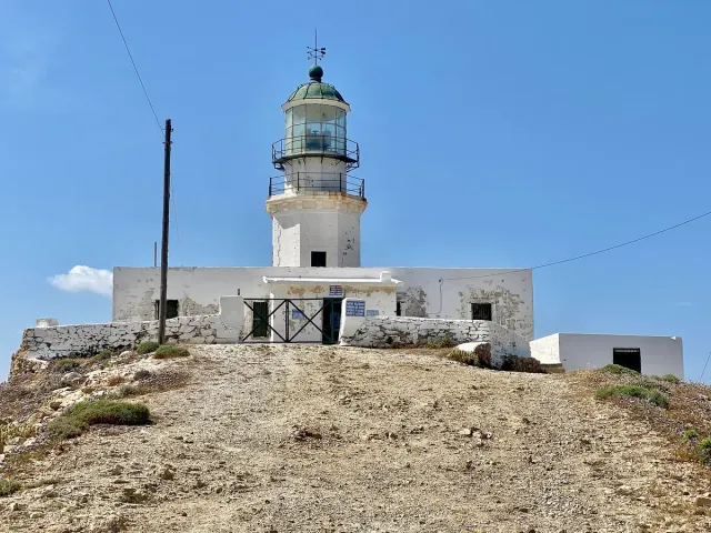 A white lighthouse with a keeper's house on a bare hill facing the sea