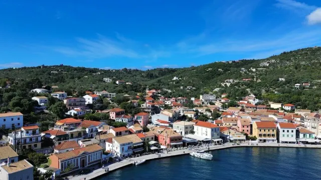 A view from above of a harbour town with tiled roofs, boats and green hills