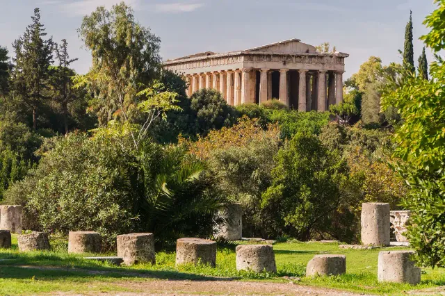A well preserved Doric temple with rows of columns, surrounded by green trees
