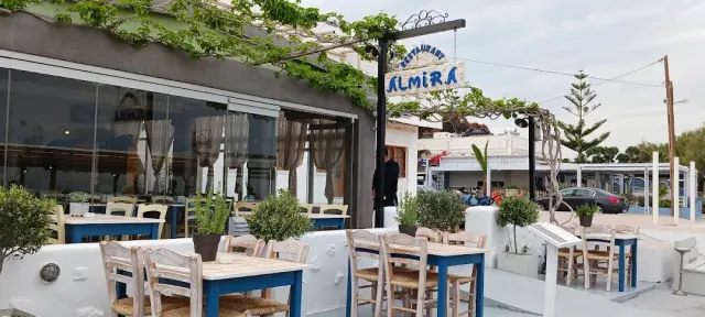 A frontage with a decorated iron sign, wooden tables outside and a climbing vine