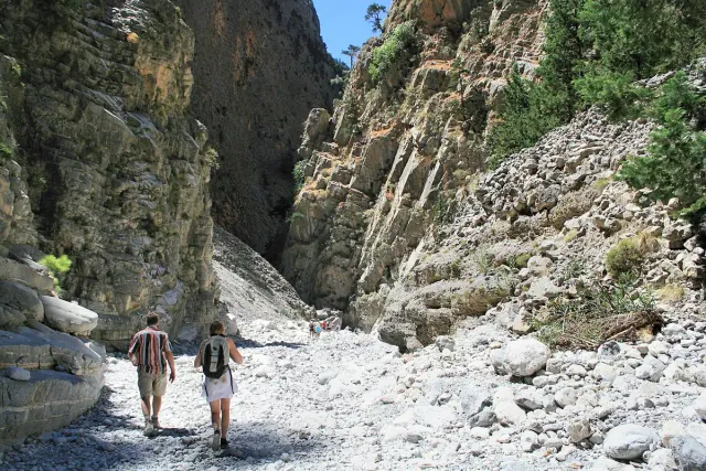Two hikers on a stony trail between high rock walls
