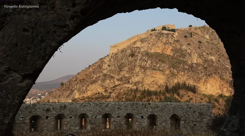 A hilltop fortress seen through a stone arch
