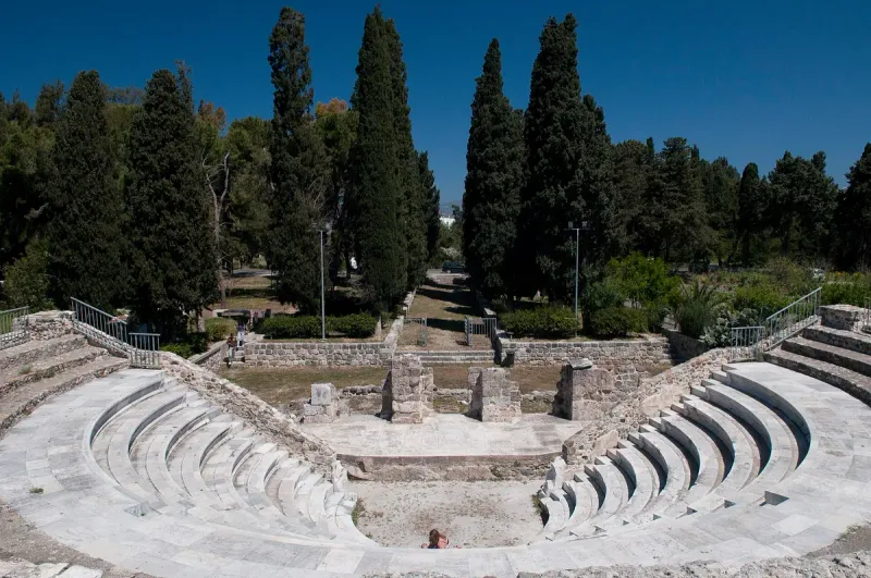 Rows of stone seating at the Roman Odeon in Kos town, surrounded by cypress trees