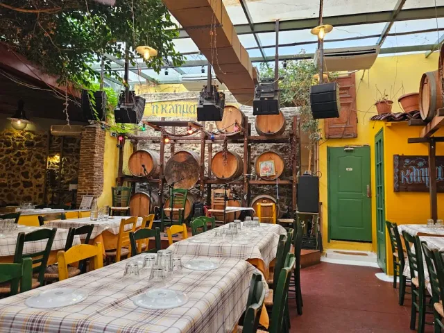 A covered courtyard with wine barrels on a rack, yellow walls and a green door