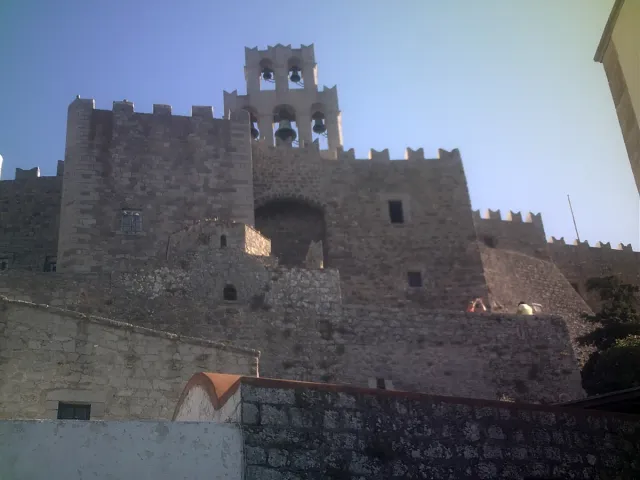 Fortified stone walls with battlements and a bell tower at the top