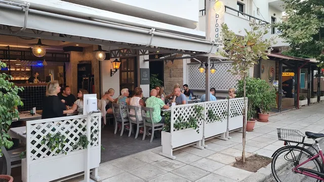 Diners seated on a restaurant terrace fenced with white lattice on a city pavement