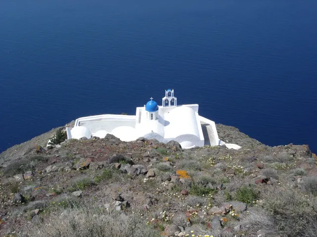 A small white church on a rocky spur above the sea