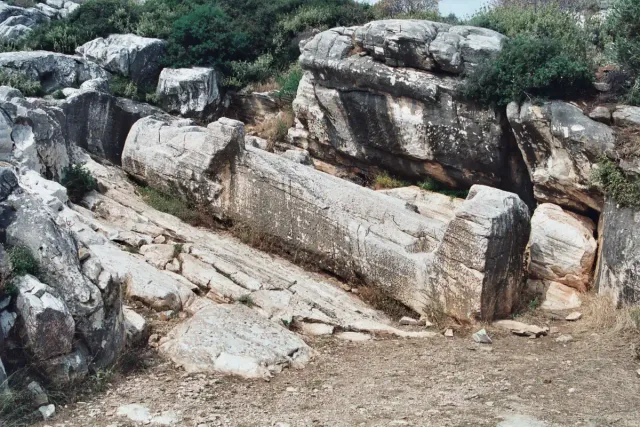 A huge unfinished stone statue lying on its back in a quarry