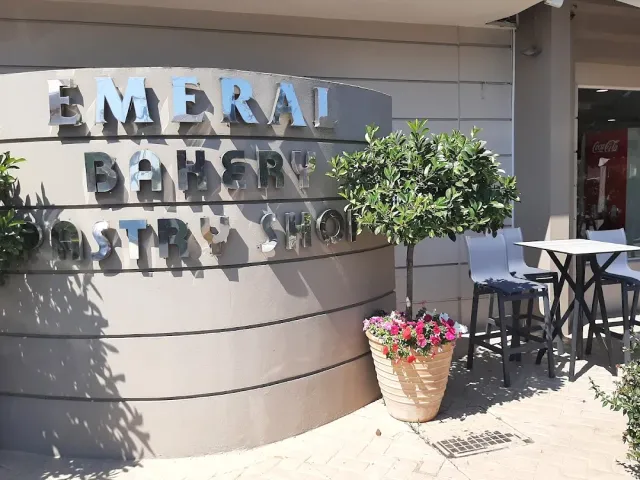 Metal letters on a curved wall, a flower pot and high tables beside it