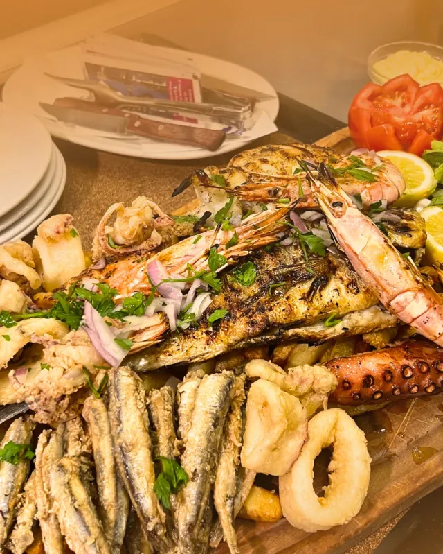A platter heaped with fried small fish, calamari rings, an octopus arm and grilled shrimp
