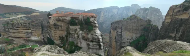 A stone monastery on top of a rock pillar, with cliffs and a valley around it