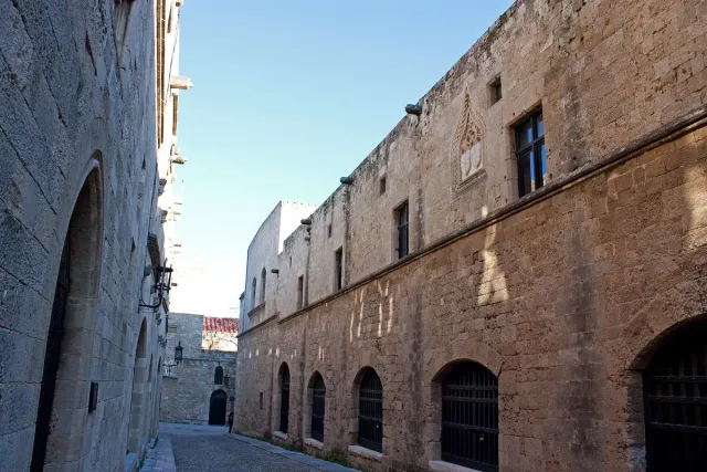A stone paved street between medieval stone buildings with arched gateways