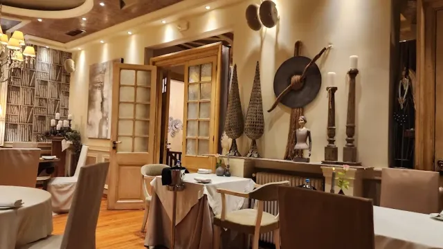 A sand toned dining room with wooden doors, a hanging shield and fabric covers on the chairs