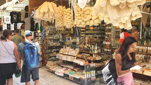 A market shop with hanging natural sponges, shelves of products and visitors in the aisle