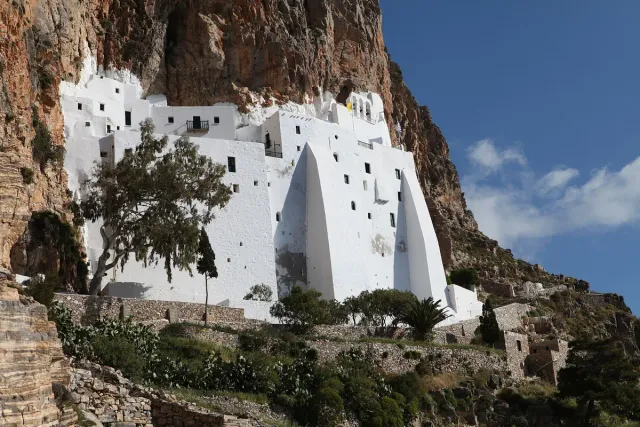 A narrow white monastery pressed against a steep rock face