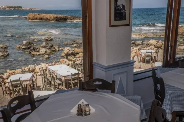 A view through a window onto white tables on rocks at the waterline