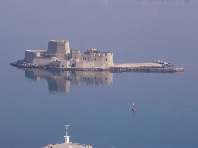 A small stone fortress standing in the water opposite a harbour