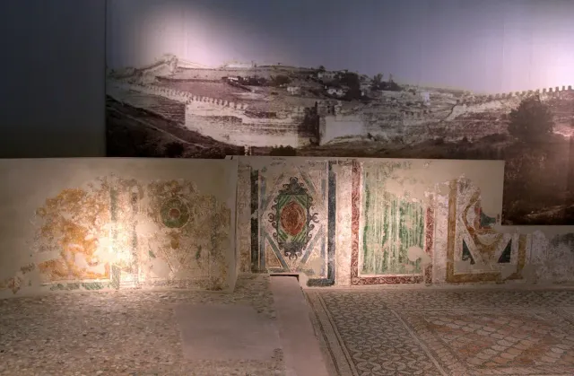 An exhibition space with painted walls and a reconstructed mosaic floor