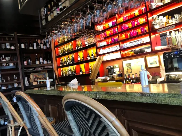 A green marble counter, lit shelves of wine bottles and glasses hanging above