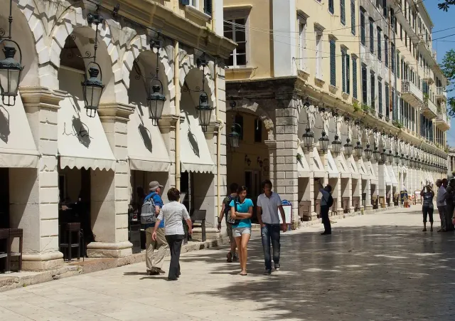A covered arcade of arches with cafes, and people walking on the paving