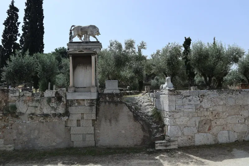 A bull sculpture on a grave marker in an ancient burial ground with olive trees