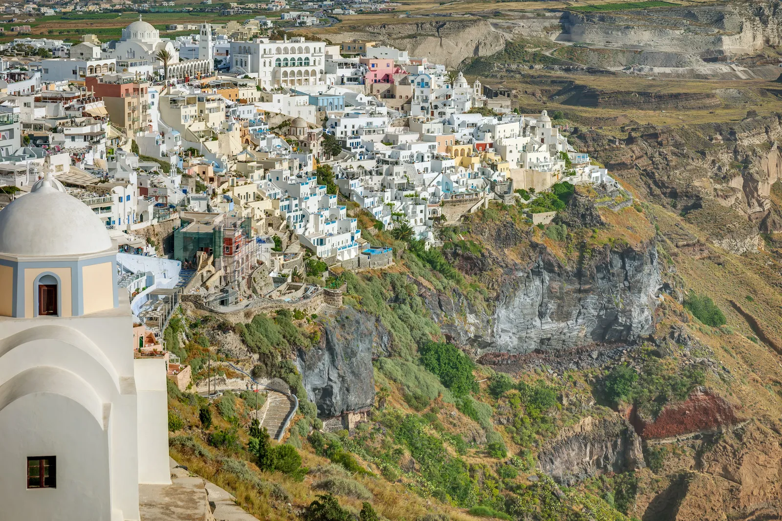 The town of Fira spread along the top of the caldera cliff in Santorini above the sea