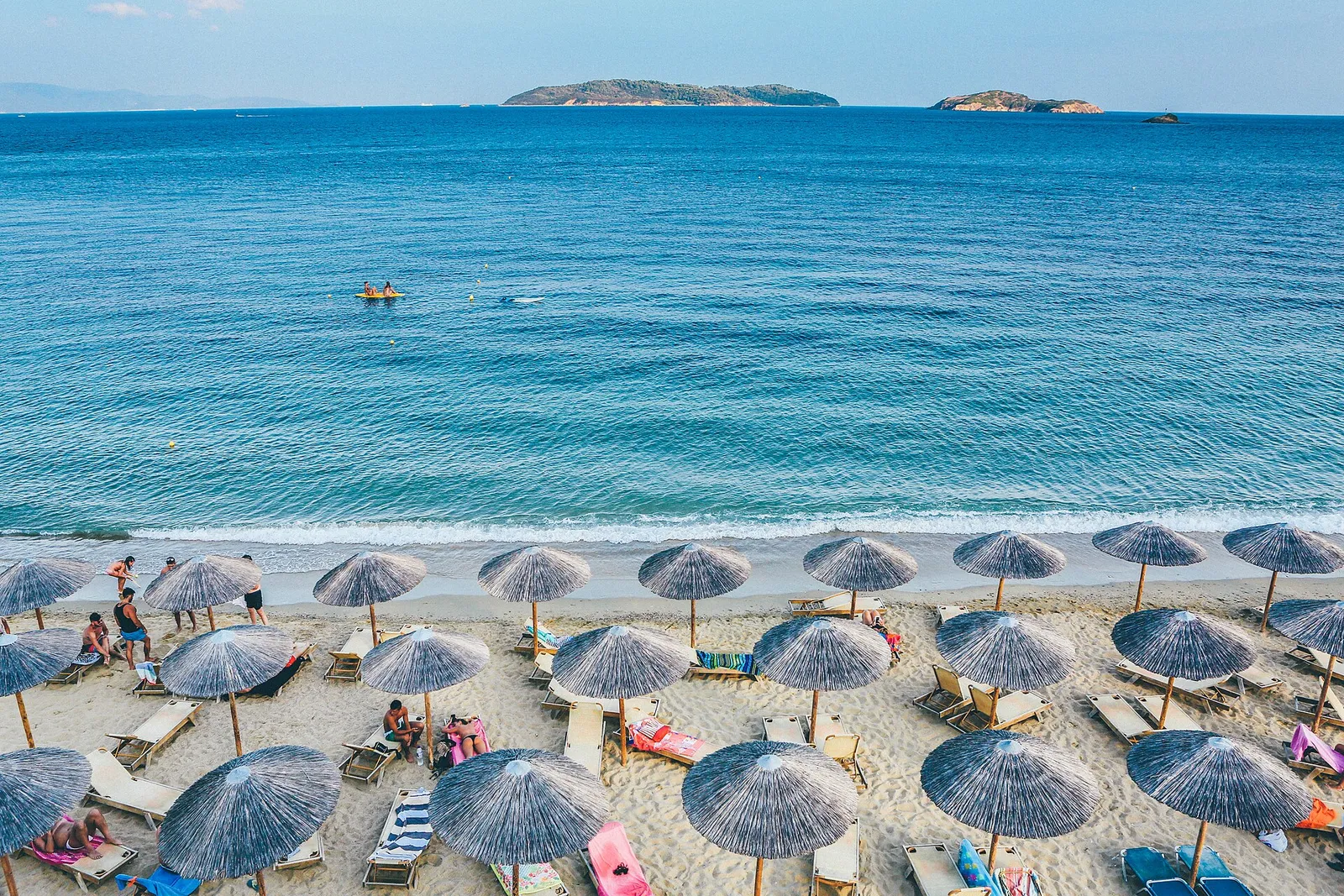 שדה פרחי בר פורחים באביב באי יווני עם כפר לבן וים תכלת ברקע